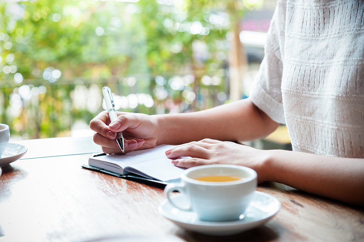 Person sitting at table and writing in journal