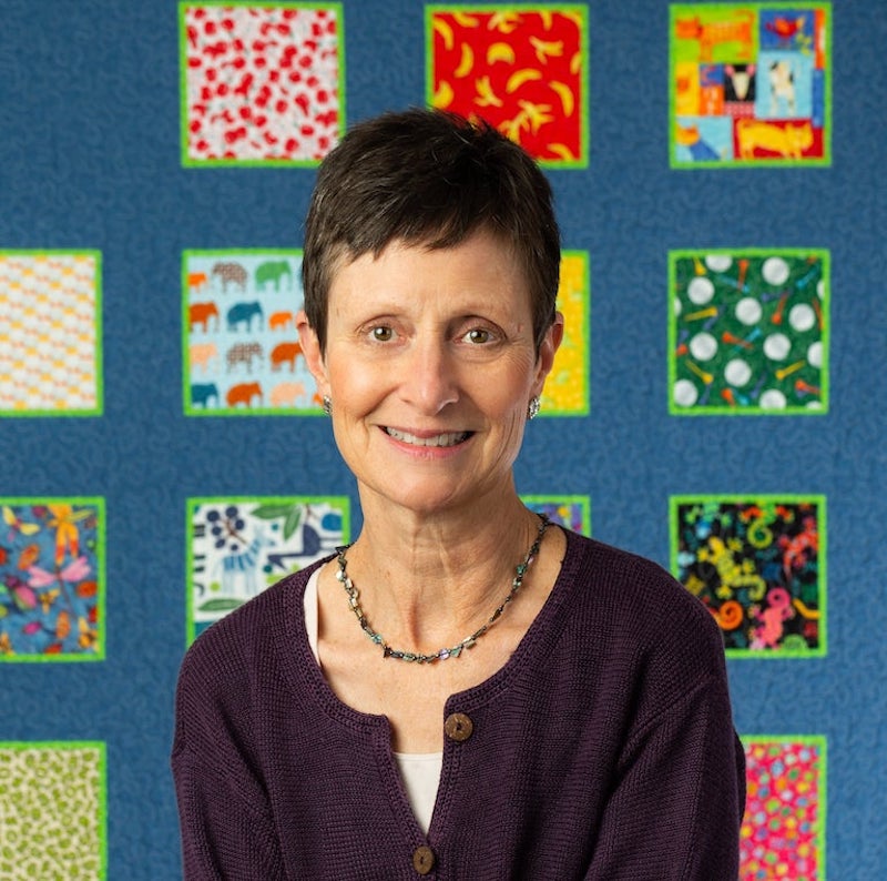 Yvonne Malone sitting in front of ABC Quilt