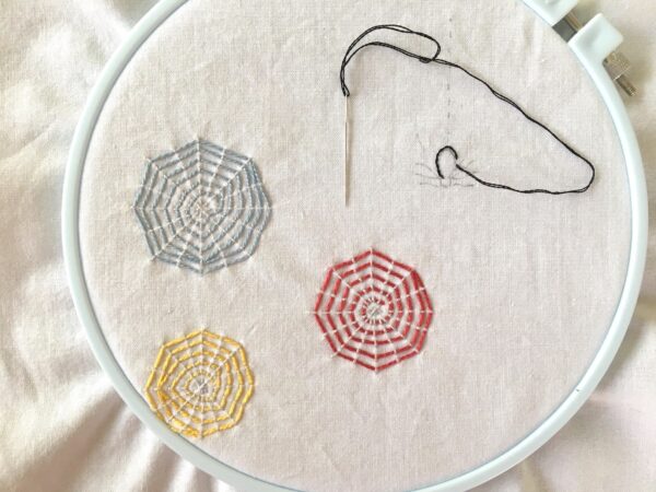 Colorful Webs and embroidery project featuring a spider and three webs in an embroidery hoop