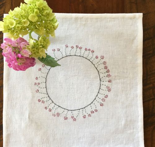 Ring of flowers embroidered on white linen